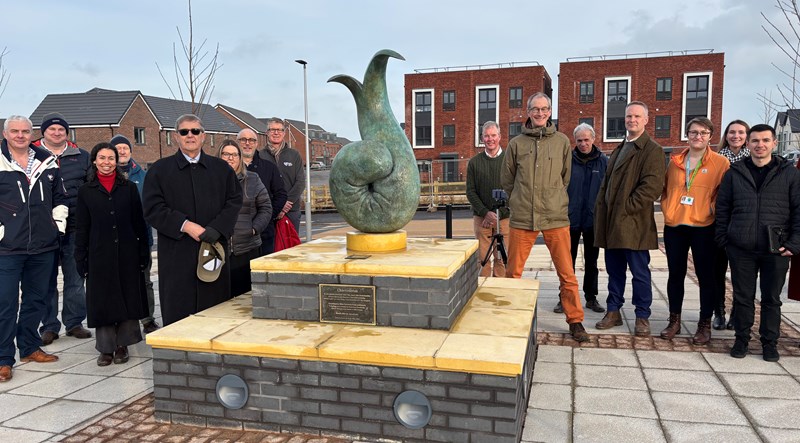 Photograph of town centre statue with multiple people standing behind it at the unveiling.